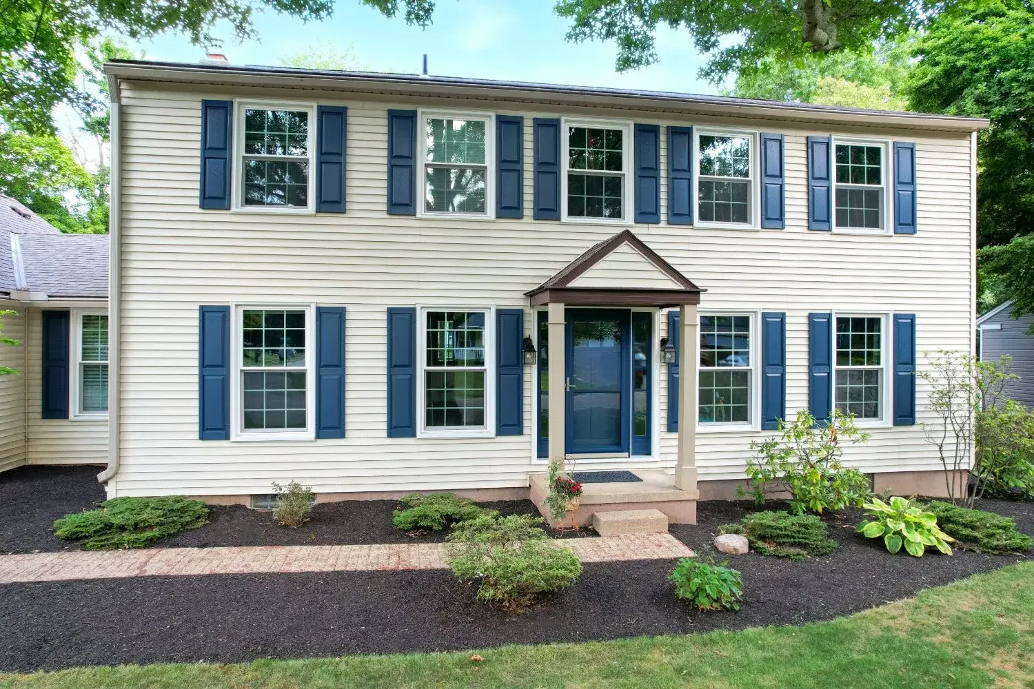 Two-story colonial home with blue shutters and a covered front entry