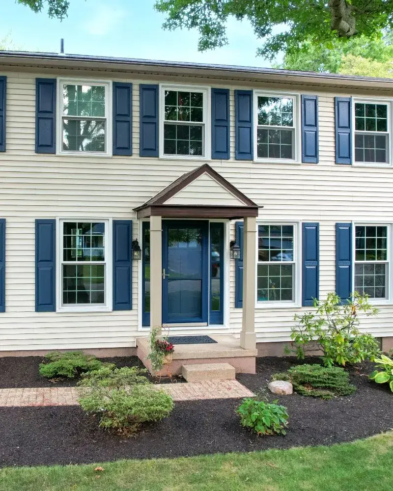 Two-story colonial home with blue shutters and a covered front entry